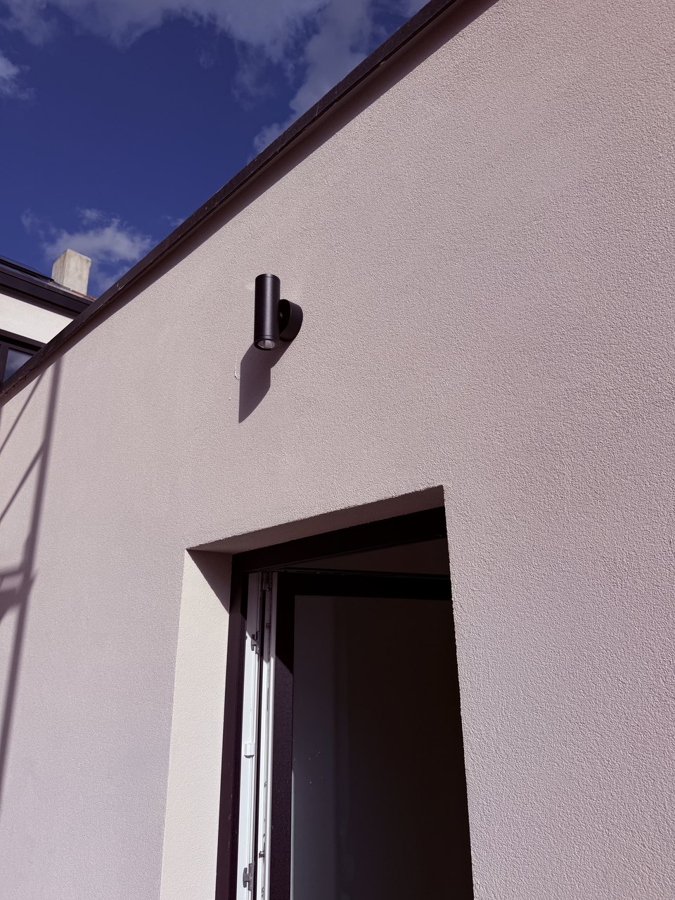 Zwarte buitenarmatuur op de gevel van de gerenoveerde woning in Burcht