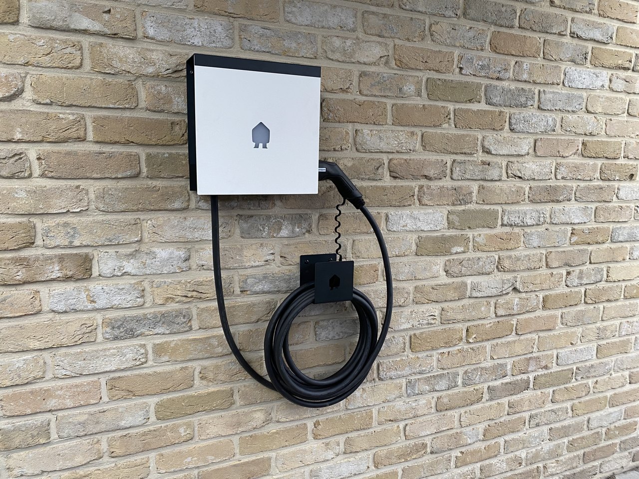 Smappee-laadpaal met nette kabelafwerking aan een bakstenen gevel