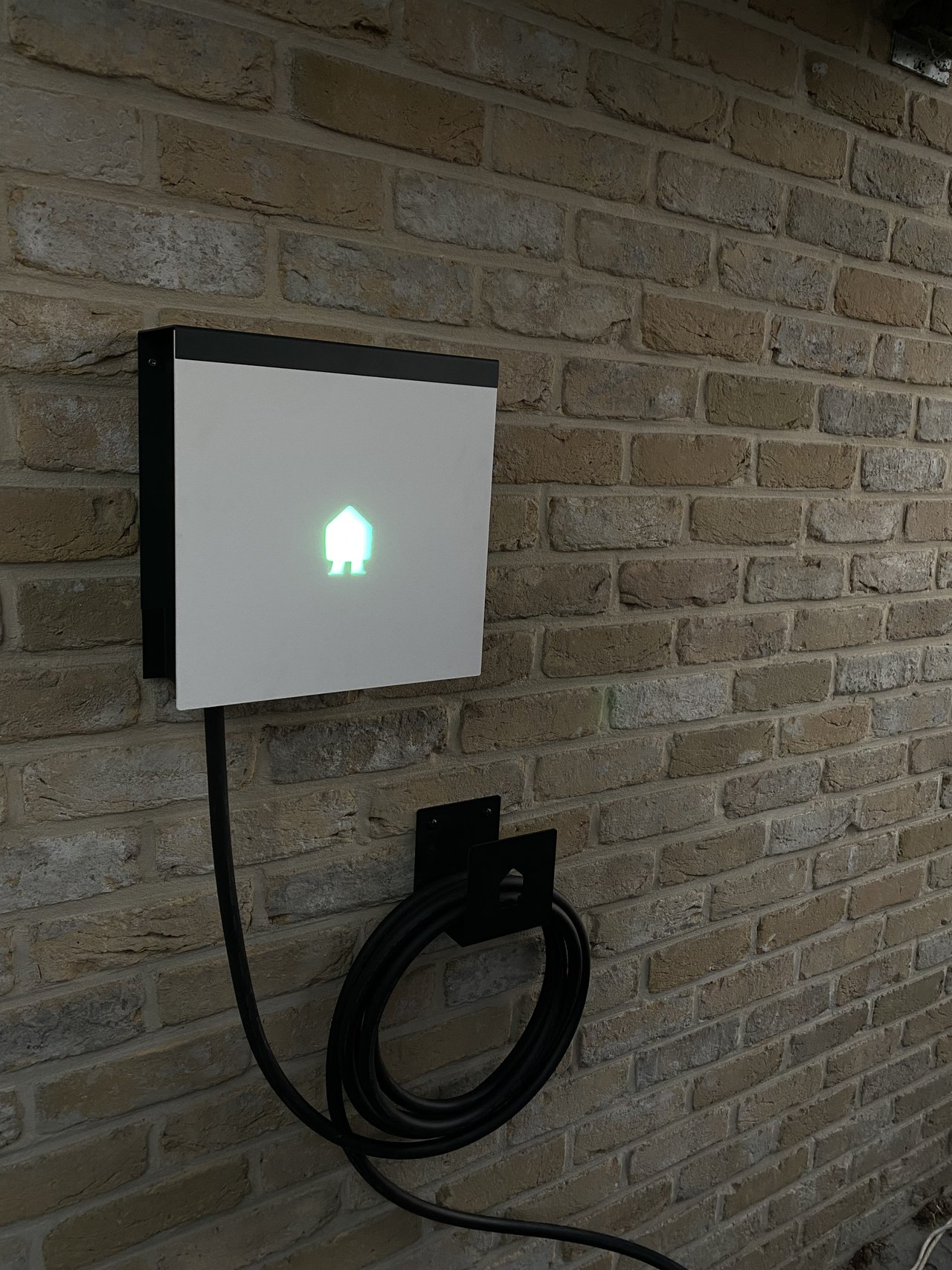 Smappee-laadpaal met groen statuslicht aan een bakstenen gevel